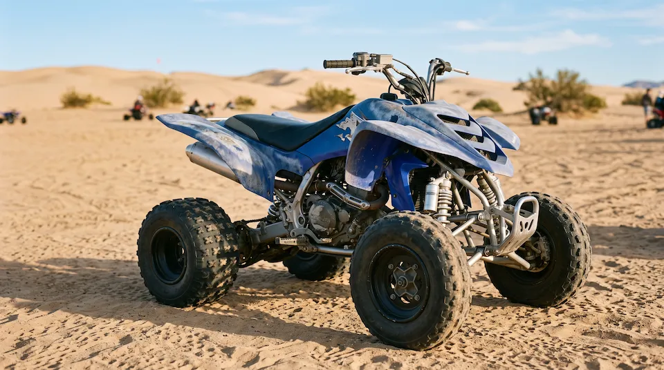 Older sport quad with sun-faded, chalky blue plastics parked at a sand dune staging area