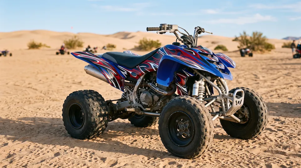 After: the same quad with bold blue, red and white flame graphics, looking new at the dunes